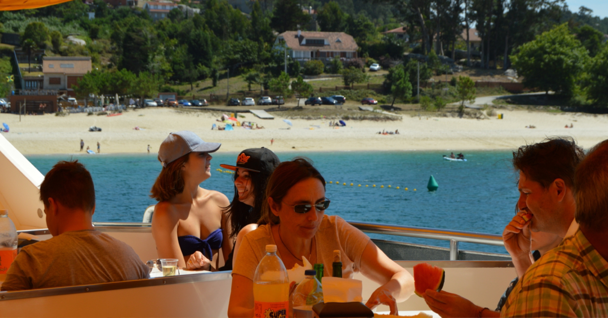 Pasajeros comiendo a bordo del barco restaurante marinero fondeado cerca de la playa de As Pipas