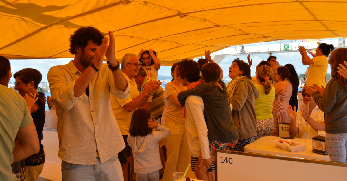 Grupo de pasajeros bailando y celebrando en la cubierta del catamarán. La fiesta a bordo está garantizada